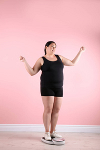 超重妇女在运动衫使用附近颜色墙壁鳞片