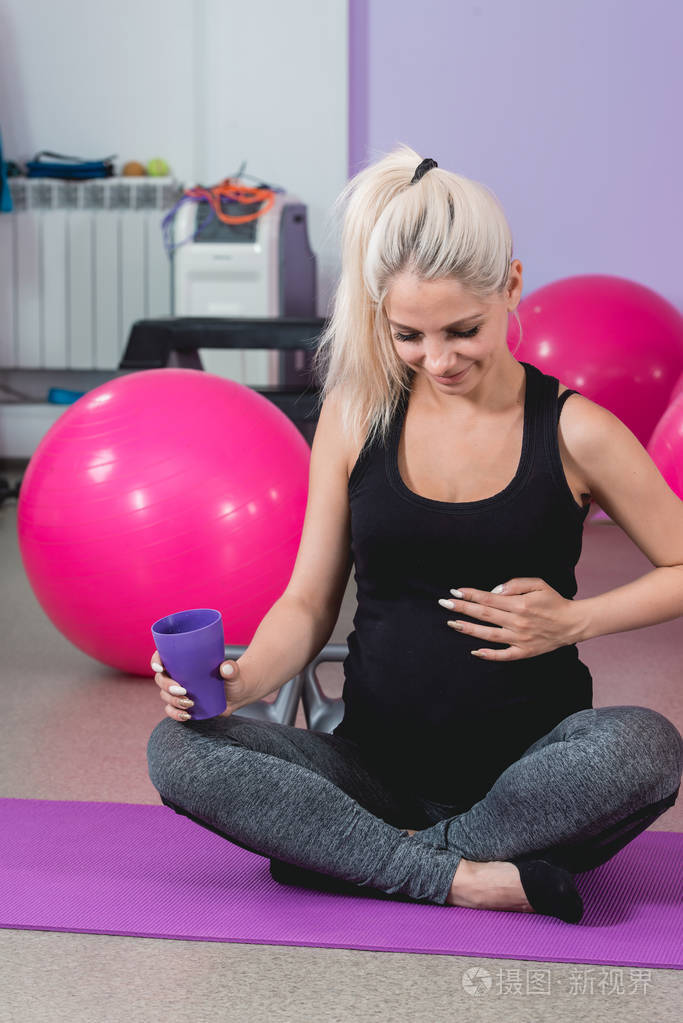 孕妇在健身房坐在垫子上放松训练后保持身体健康