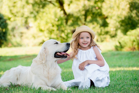 小可爱的婴儿金发女孩玩她的大白牧羊犬。选择性聚焦