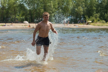 在海滩上训练一个年轻人。一个年轻人在早晨慢跑在新鲜的空气