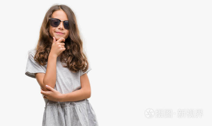 穿着太阳镜的黑发西班牙女孩对着相机充满自信, 带着交叉双臂和双手举起下巴。积极思考