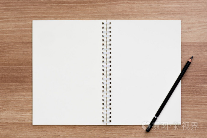 用一支铅笔在木质表面上打开空白活页螺旋装订笔记本
