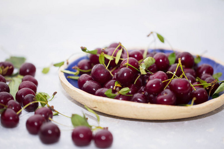 新鲜的樱桃放在桌子上的盘子里。野生浆果,健康维他命和夏日概念