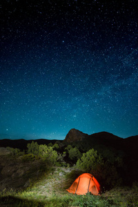 照亮了露营旅游帐篷在山下的星空夜空。户外和旅游概念