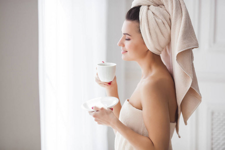 美丽的妇女在毛巾沐浴后喝了早晨的咖啡