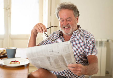在吃早饭和喝咖啡的同时读报纸的快乐老人的画像。快乐的老年退休理念