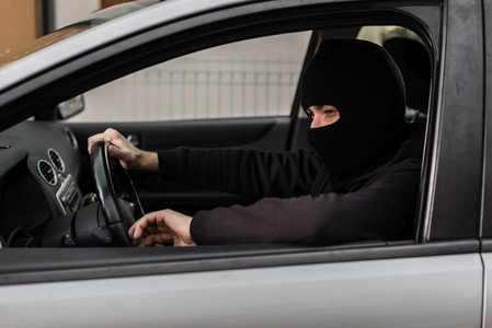 驾驶一辆被盗的汽车的偷车贼照片