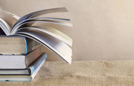 打开书在老课本堆上面在桌以麻布背景,大学学习概念,特写与拷贝空间或