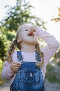 夏天在花园里吃樱桃的快乐小女孩。孩子在花园里吃浆果