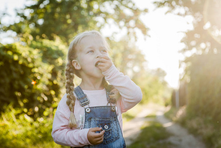 夏天在花园里吃樱桃的快乐小女孩。孩子在花园里吃浆果