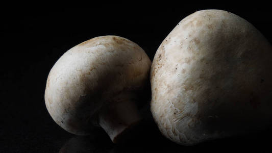 在黑色的背景上关闭美味的白色蘑菇。框架。适当营养的概念