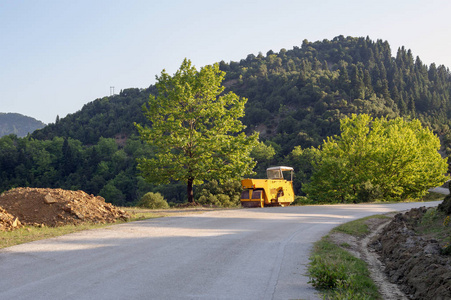 一个阳光明媚的夏日, 涂柏油路路的土压机停在山上的路旁。