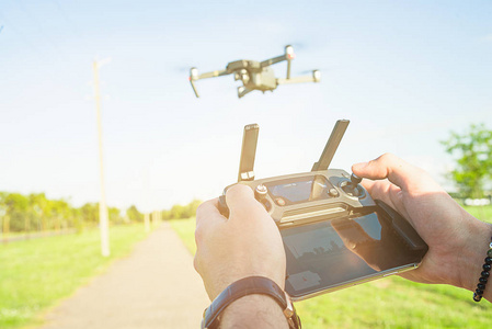 飞行 quadcopter 无人机与行动相机在蓝天下的空气和遥控在手