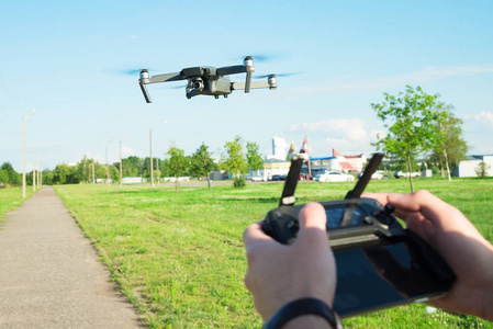 飞行 quadcopter 无人机与行动相机在蓝天下的空气和遥控在手