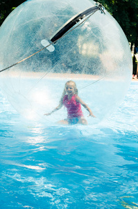 小孩在漂浮在水中游泳池充气球里面