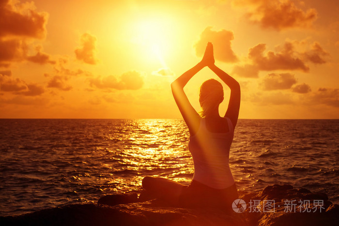 年轻健康的女性练习瑜伽中的石头,在夏天阳光灿烂的日出背景在莲花