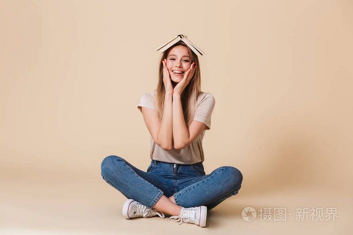 正面金发女人的照片穿着牛仔裤覆盖脸与手, 而坐在地板上莲花的姿势与