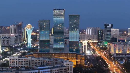 鸟瞰在市中心和中央商业区从天到夜转折时差从屋顶, 中亚, 卡扎克斯坦, 阿斯塔纳。道路交通