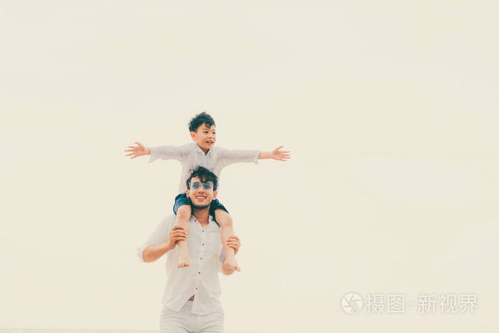 快乐的父亲在夏天的热带沙滩上背着儿子的脖子上
