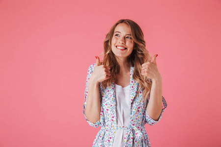 一个满意的年轻女子的肖像, 在夏季礼服显示大拇指向上孤立的粉红色背景