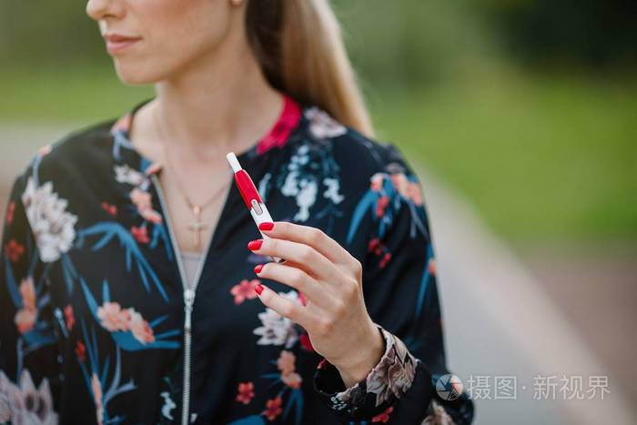 美丽的女孩使用电子香烟.烟草系统 iqos