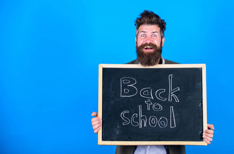 老师胡子人站立并且拿着黑板与题字回到学校蓝色背景。老师邀请继续学习。继续与我们的教育。新学期