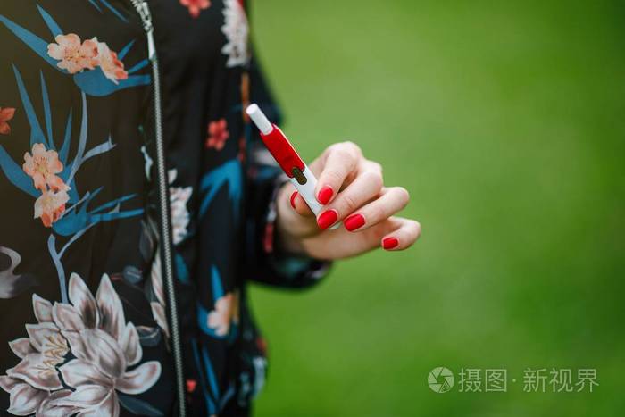 美丽的女孩使用电子香烟.烟草系统 iqos