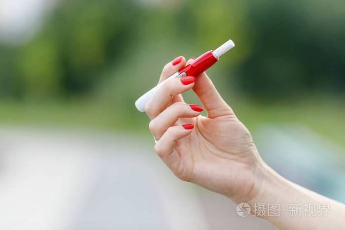 美丽的女孩使用电子香烟.烟草系统 iqos