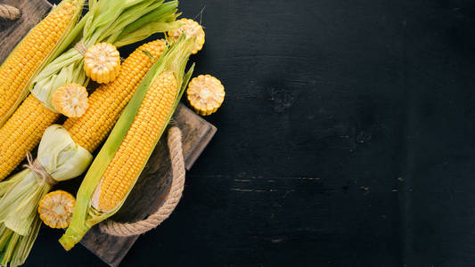 黑色木桌上的鲜黄色玉米。蔬菜。顶部视图。复制空间