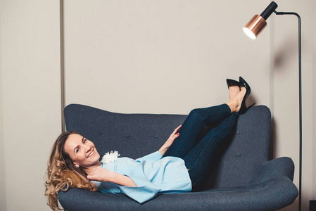 优雅的女人坐在沙发上穿着时髦的高跟鞋.