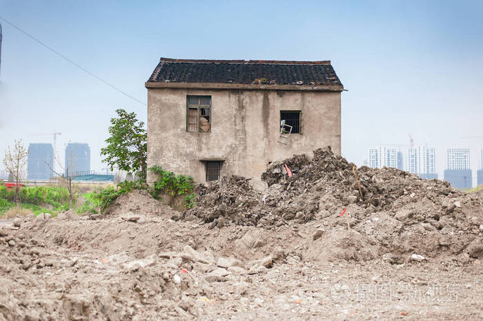 废弃的旧房子周围的瓦砾和泥浆准备被拆除与摩天大楼的背景 正面射击