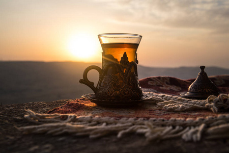 东部地毯上玻璃上的东方红茶。东方茶的概念。Armudu 传统杯。日落背景。选择性聚焦