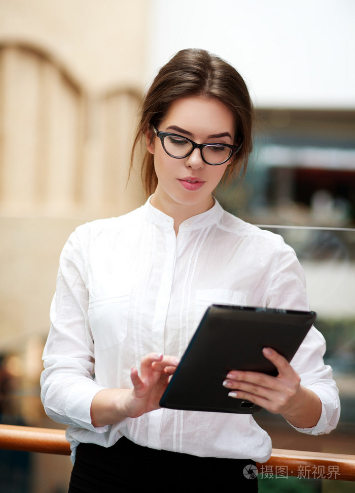 在平板电脑站在室内工作的年轻商界女强人