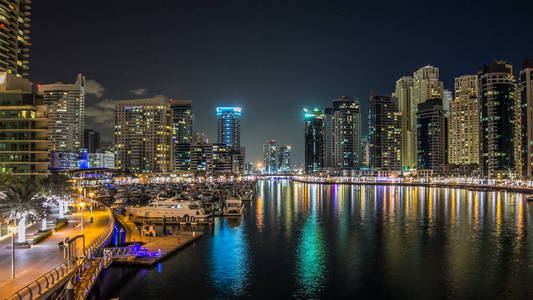 美丽的夜景从桥上迪拜滨海塔闪烁的灯光反映在水中的浮动游艇和船只 timelapse hyperlapse, 阿拉伯联合酋长国。迪