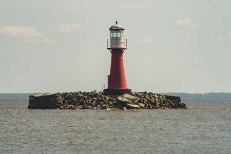 靠近一个小岛上的红色灯塔, 水中有岩石