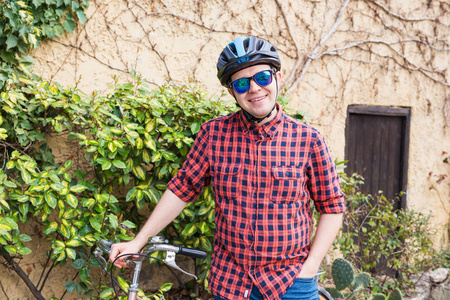 戴头盔和眼镜的男子留在自行车背景花园
