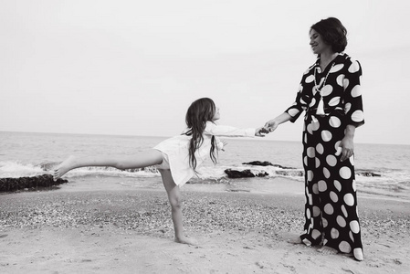 黑白照片的母亲和女儿在沙滩上玩得开心