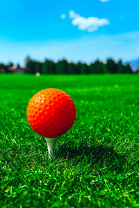 高尔夫球红色球在三通, 绿色草领域, 蓝天, 宏观看法