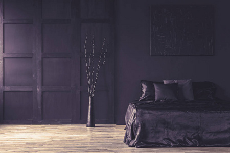 雕塑旁边的床在黑暗的卧室内部与木墙和地板。真实照片