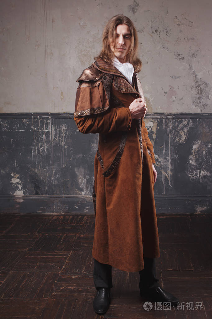 在棕色的斗篷蒸汽朋克风格的英俊男性复古男人肖像grunge的背景