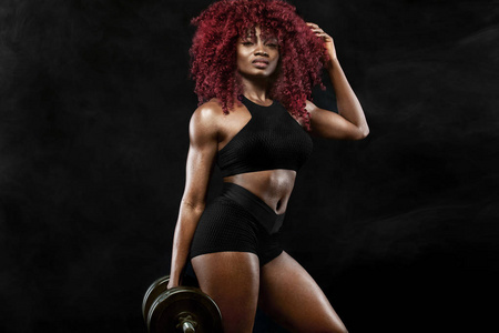运动型美女与哑铃使行使在黑色背景的健身以保持健康