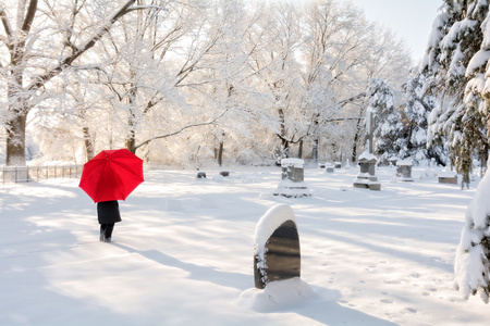 冬天墓地里有一把红色雨伞的人, 地上有雪。