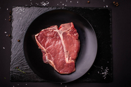 生肉, 牛排, 猪肉或小牛肉, 羊肉, 躺在黑色的陶瓷板上, 在黑色的石板上。顶部视图。复制空间