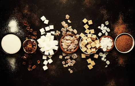 一套不同的白色和褐色的糖在分类, 黑暗的背景, 色调的图像, 顶部视图