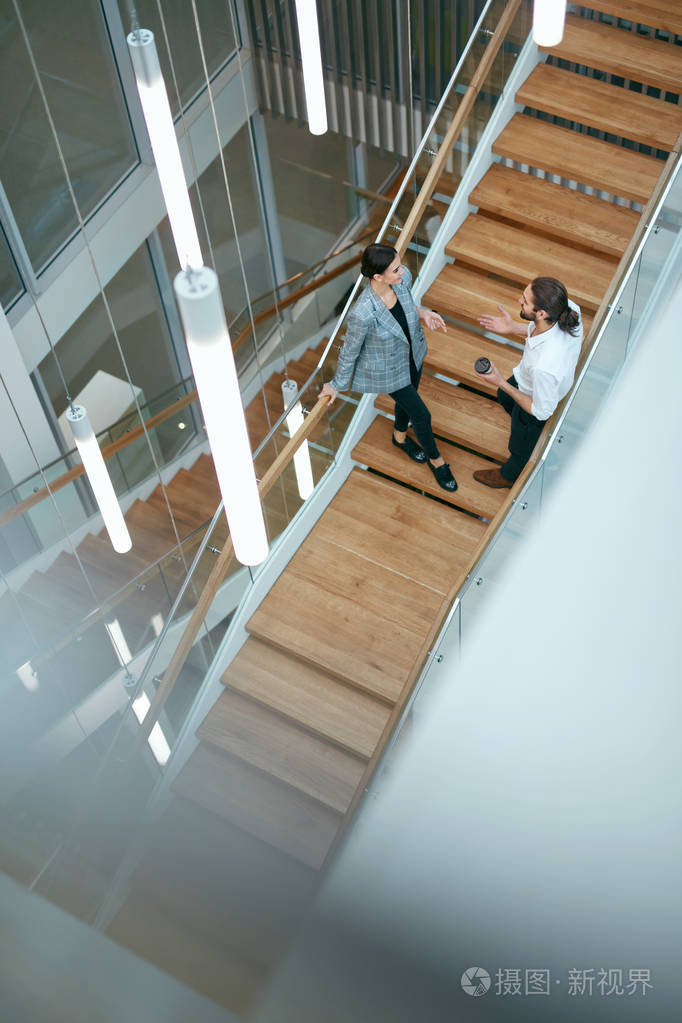 男人和女人在楼梯上走在现代商务中心的内部.高分辨率