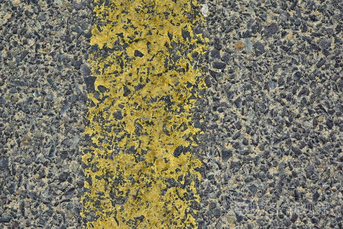 沥青路面上一条破旧的黄色反光路标志特写