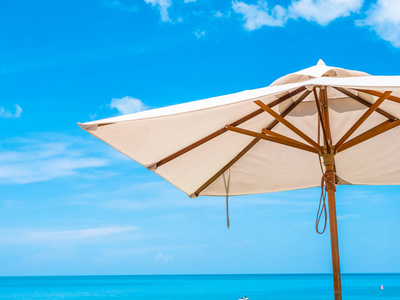 白色伞与椰棕榈树与海洋在蓝天背景为旅行和假期
