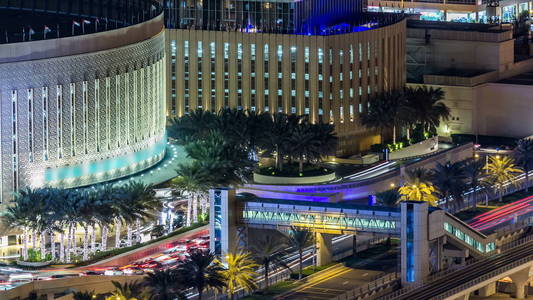 美丽的空中顶视图的购物中心在晚上游戏中时光倒流在迪拜，阿拉伯联合酋长国的迪拜码头附近的交通。照明现代塔与闪烁的灯光和交通道路 