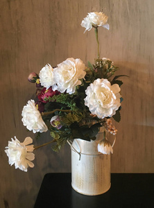 白色玫瑰组合在花瓶反对棕色背景。复古装饰花