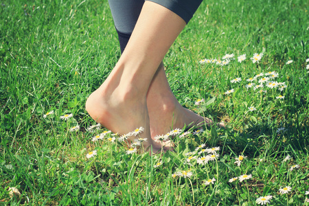 女人赤脚走在绿草上.照片